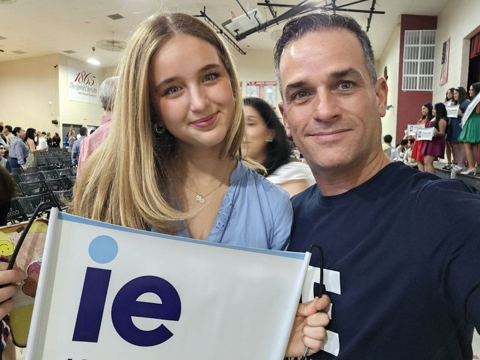 Gabriel and Ximena smiling together while holding an IE flag.